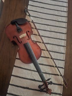 violin and its bow, resting on a striped textile runner. 