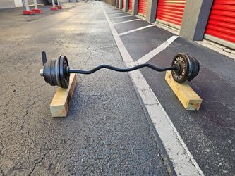 💯 pounds Weight Weight plates over.
Black EZ curl bar loaded with cast iron weight plates on both ends, secured with spring collars. Plates show w