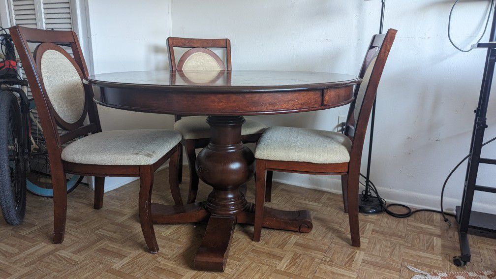 Vintage round dining table with four upholstered wooden chairs