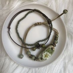Two adjustable string charm bracelets and one bead bracelets