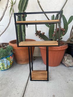 industrial-style multi-tiered floating wall shelf featuring a black iron bracket frame and rustic wooden planks.
