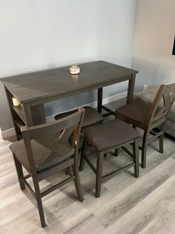 Grey dining table with 2 chairs and 2 stools.