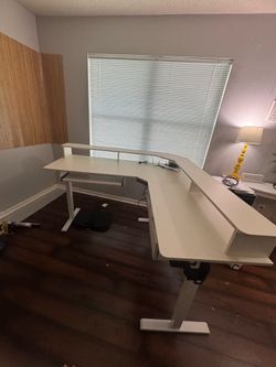 White L shaped electric standing and sitting desk.