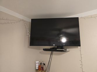 A RCL tv and a Samsung DvD player and a Sanus glass wall shelf and three remotes