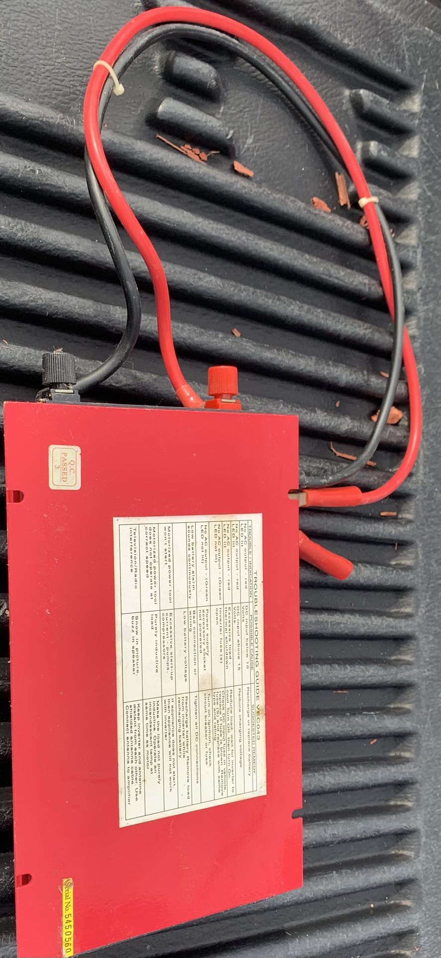 Red power inverter with attached cables.