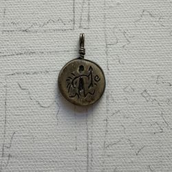handmade pendant or amulet. It features an engraved symbol or pictogram
