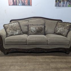 Dark Beige Fabric Camelback Couch With Throw Pillows and Wood Trim
