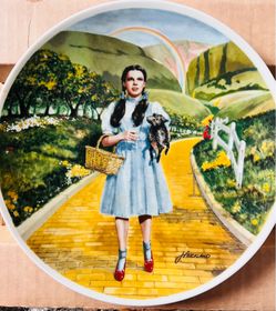 This collector plate is the "Over the Rainbow" edition from the Knowles Wizard of Oz collection, featuring Dorothy and Toto walking on the yellow bric