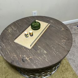 Round gray wood-top coffee table with a metal cage base