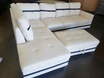 Contemporary white faux leather sectional with a matching storage ottoman