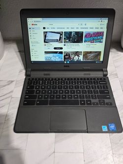 Functional Dell Chromebook has a black carbon fiber textured skin on the lid. The device is dark gray with a standard QWERTY keyboard and integrated t