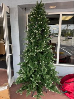 artificial Christmas tree features realistic, lightly snow-flocked branch tips and warm LED lights