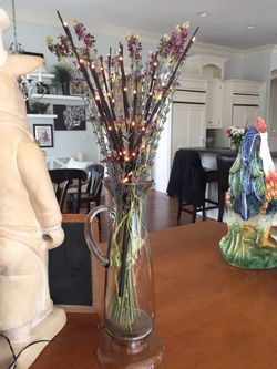 Decorative pitcher or vase , lights and flowers.