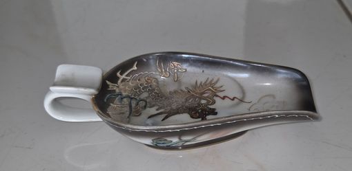 Vintage collectible Japanese ceramic ashtray in large spoon shape with handle. Raised hand‑painted dragon motif with gold detailing, grey‑white glaze