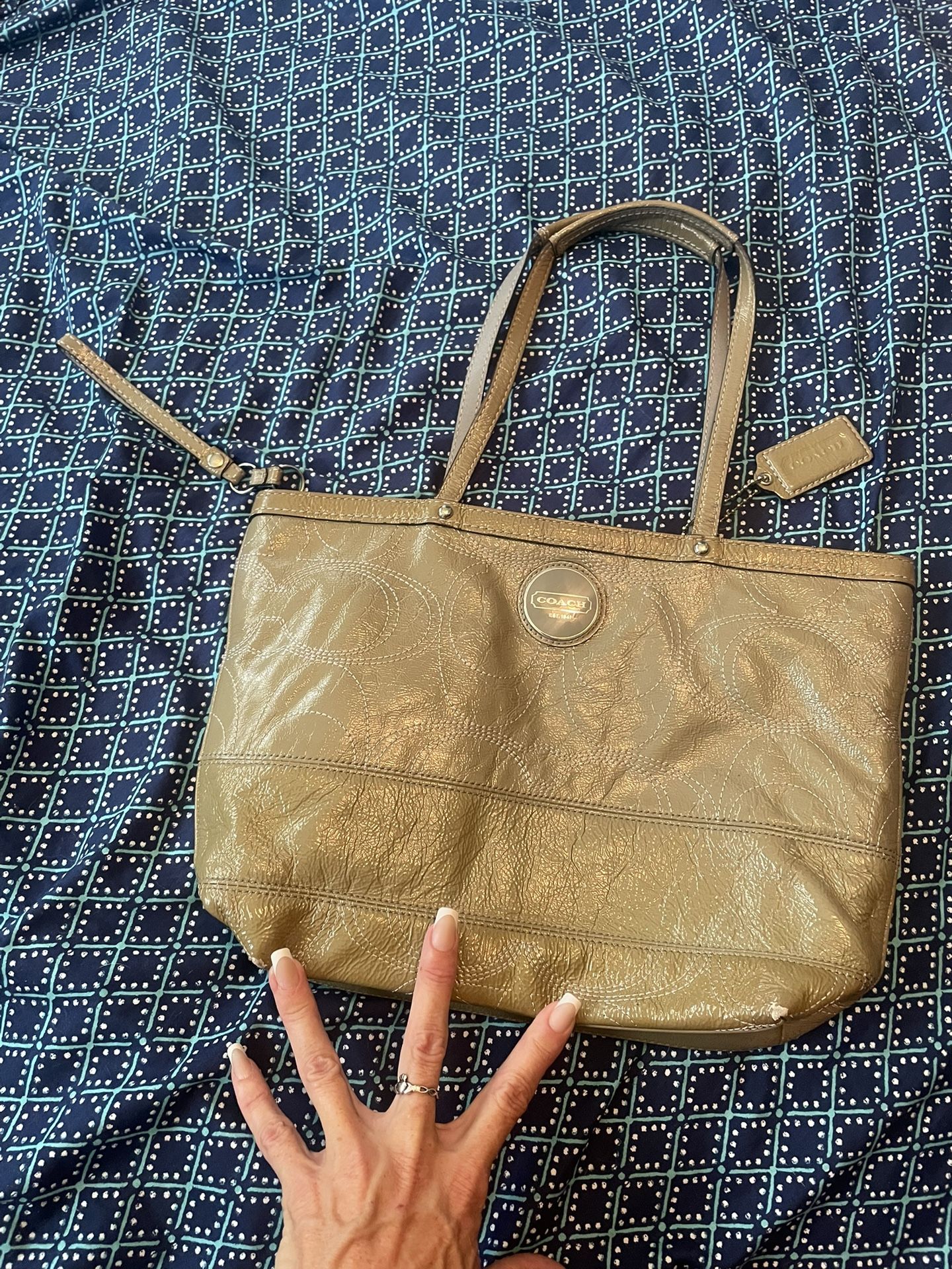Green coach purse with white coach stitching for a design on the outside with silver hardware