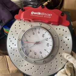 QwikStop Performance Disc Brake Caliper Wall Clock. It's a novelty clock designed to look like a car brake rotor and caliper, often used as decorative