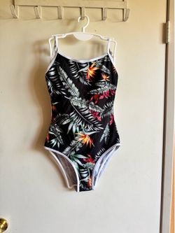 Comfortable one-piece swimsuit in black with vibrant tropical print. Features bold green foliage and orange, red, and yellow floral accents. Soft fabr