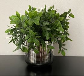 Large luscious artificial green plant in a ribbed, metallic silver pot.