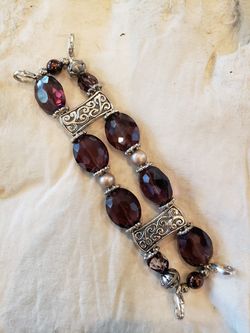 Handmade purple glass bead bracelet. Silver charm accents. Four lobster clasps. Bracelet is 5.5 in long. 1.25 in wide.