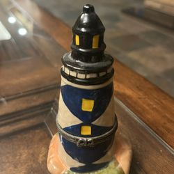 This nautical lighthouse trinket box will have you daydreaming about the beach. Measures 4 x 2 1/4 x 1 3/4 inches Made of porcelain Hand-painted Conta