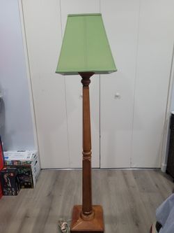 This vintage floor lamp features a wooden cherrywood base and a green fabric lampshade.