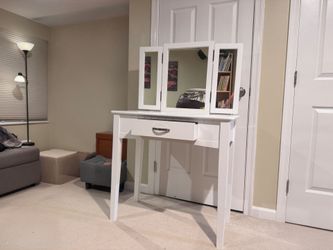 White wooden vanity with a tri-fold mirror