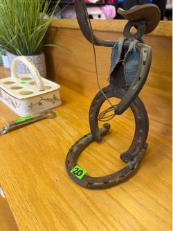 rustic cowboy sculpture is crafted from repurposed iron horseshoes and features a denim fabric vest.