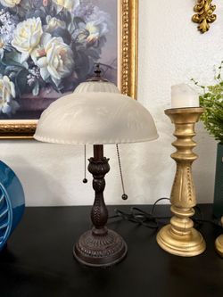 vintage-style table lamp featuring a dark bronze-finished metal base and an etched frosted glass dome shade with a delicate floral pattern.