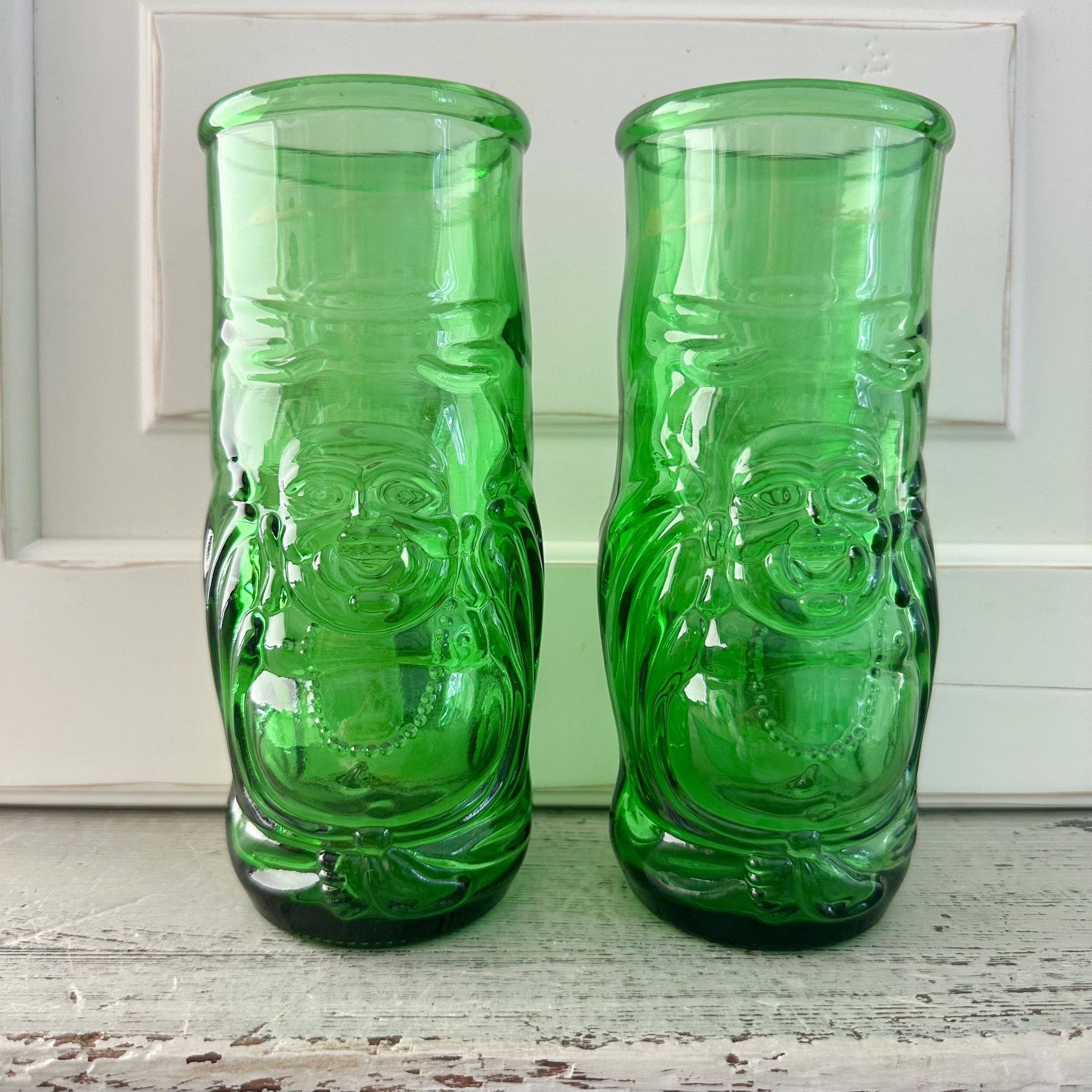 Set of 2 green glass lucky Buddha beer bottle glasses They are 7” Tall. They are 2 7/8” across the tops. They hold 16 ounces.