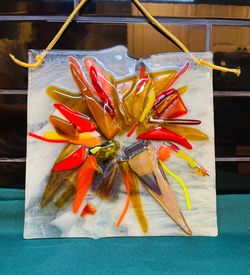 Beautiful artistic handmade fused art glass panel with vibrant colors in a sunburst floral design