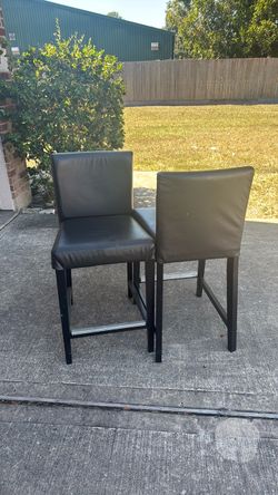 2 black leather chairs with reinforced foot rest