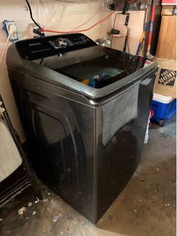 The Samsung WA51A5505AV/US is a 5.1 cubic-foot smart top-load washing machine featuring an ActiveWave agitator and a brushed black finish.