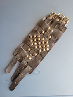 Black leather cuff bracelet featuring 3 buckles and silver-toned conical studs.