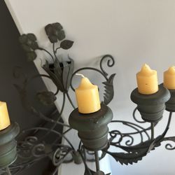 Decorative wrought iron candle holder with six yellow candles. 