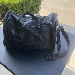 Medium Size Black Duffel Bag With A Hard Bottom, 2 Zippered Side Pockets, Front Zipper Pocket, Use Handles Or Shoulder Strap. Black