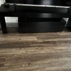 Sleek black entertainment TV stand with two storage drawers and open shelves.