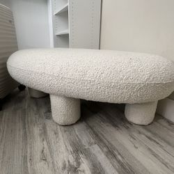 This is a cream boucle oval ottoman