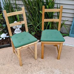 Two wooden chairs with green cushions