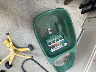 a green Scotts Turf Builder Handy Green II handheld spreader used for applying grass seed or fertilizer