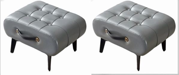 (B-20) 2  mini gray ottoman footrest features a tufted design and a black side handle accented with gold hardware.