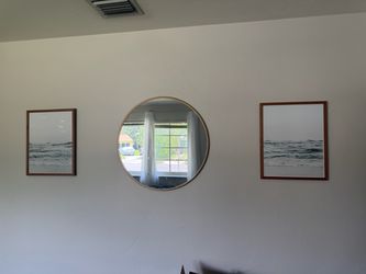 Circle mirror and two framed ocean prints