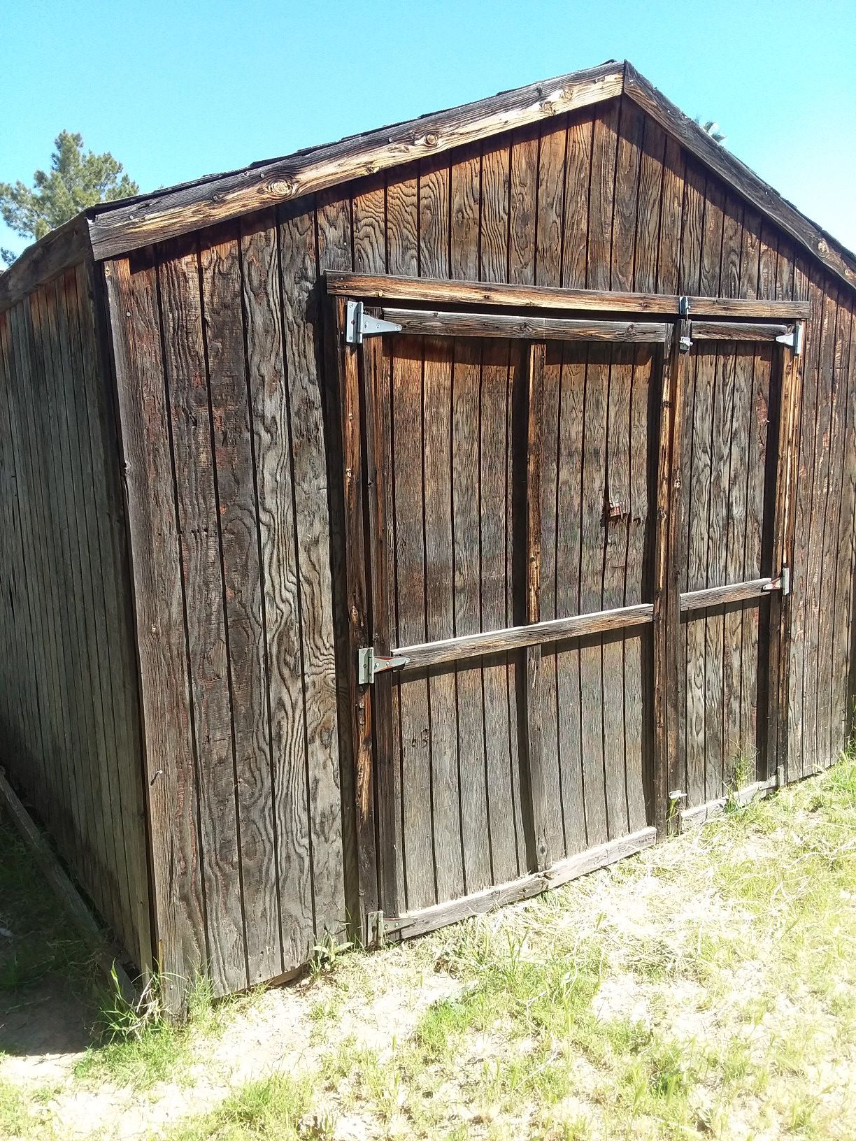 Wooden shed w/ shingled roof. 10 ft high at peak. 9 ft wide. 7 ft deep.