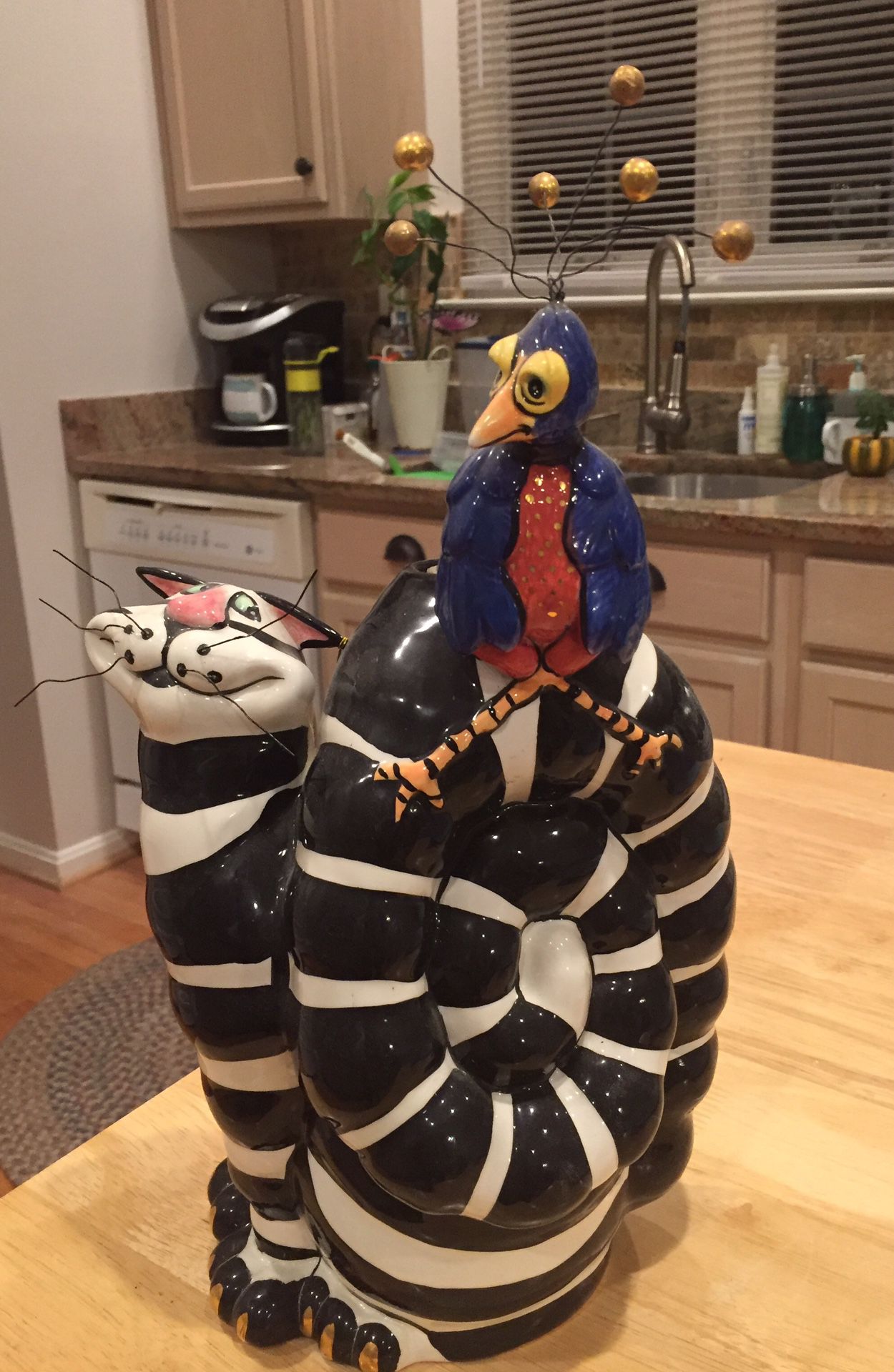 Whimsical cat and bird sculpture with tea light candle at top behind bird.