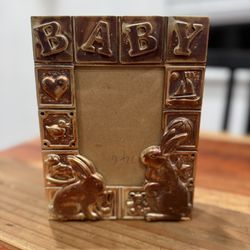 This item is a vintage, silver-plated photo frame designed for baby photos