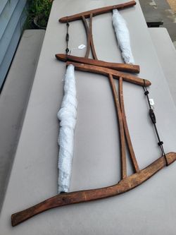 Antique wooden frame buck saws, also known as bow saws or crosscut buck saws, featuring a curved wooden frame with a metal tension rod and twisted-wir