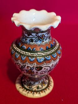 A vintage, hand-painted, ruffled-edge pottery vase with floral motifs.