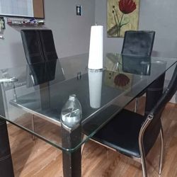 A Black Glass Table With Three Chairs