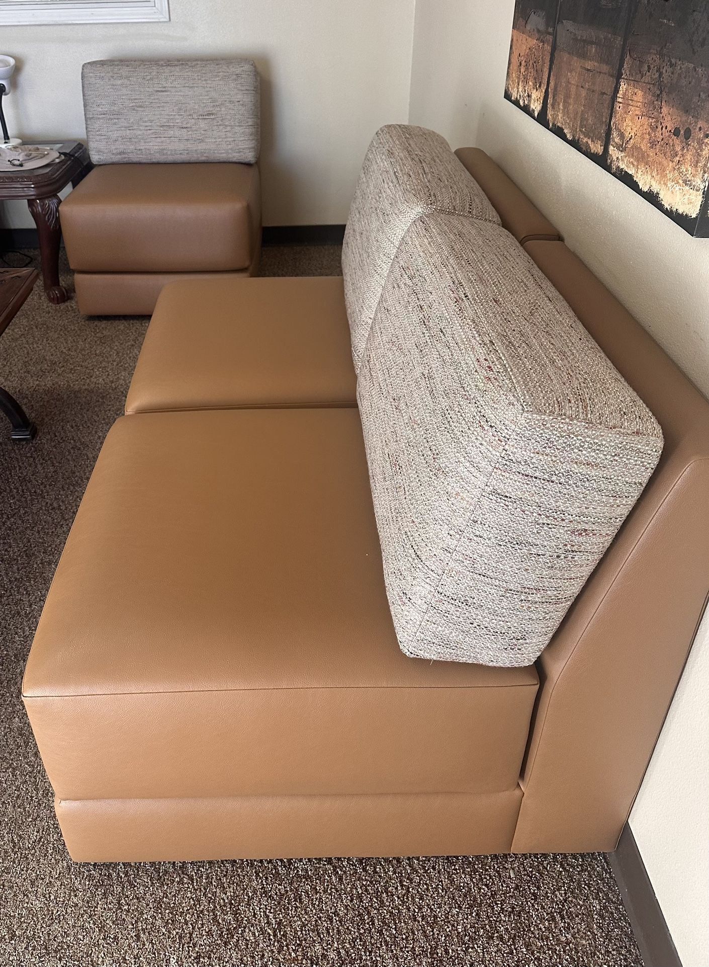 Comfortable two-seater sofas with brown leather cushions and fabric backrests.