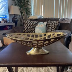 This elegant gold-toned pedestal bowl features a modern, open-lattice design with an elongated oval silhouette. Perfect as a sophisticated tabletop ce