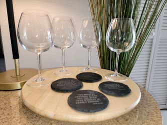 A set of clear crystal wine glasses and round, natural black slate coasters, laser-engraved with famous quotes (such as remarks attributed to Mark Twa